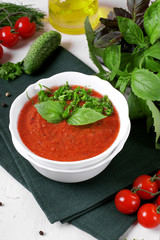 Tomato gazpacho soup in a ceramic bowl topped with basil leaves. Spanish cuisine cold soup