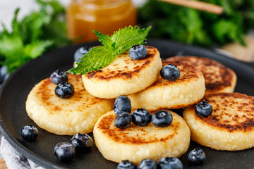 Cottage cheese pancakes with raspberry and blueberry in pan on rustic background, breakfast or lunch