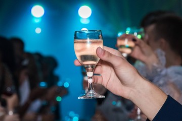 A man holding a glass of champagne in his hand in a nightclub