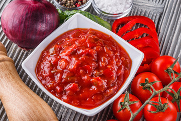 Fresh tasty tomato sauce on rustic wooden background
