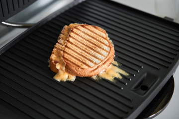 cooking panini with melted cheese on grill with golden crust