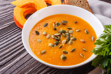 pumpkin carrot cream soup on rustic wooden background