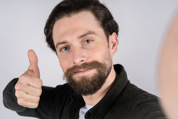 Young man hold the camera with hand and shows thumb up