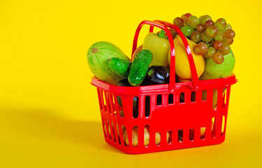 Red plastic shopping basket on yellow background