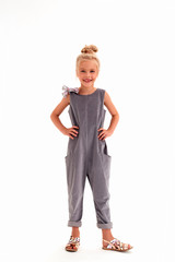 Vertical , photo of a blonde girl in full growth on a white background smiling with a toothless smile rests her hands on her hips
