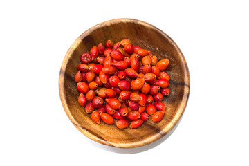 Rosehip berries in a wooden bowl isolated on white background. Top view.