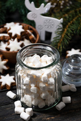 Obraz na płótnie Canvas jar with sweet marshmallows and Christmas decorations on wooden table, vertical