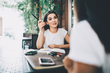 Pleased woman explaining task to new coworker at cafe