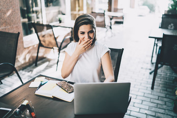 Astonished woman with smile watching laptop in cafe