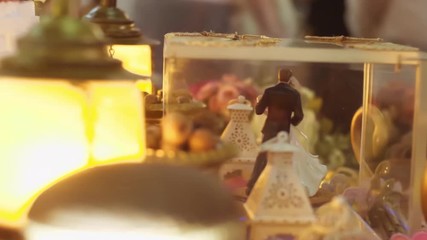 Close-up of figurine couple on wedding cake at the park. Wedding cake decorated with flowers at wedding ceremony. White cake bread for wedding. The concept of festive desserts. Spinning cake.