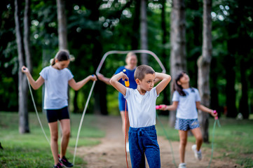 Obraz premium School children in white t shirts skipping ropes at public park