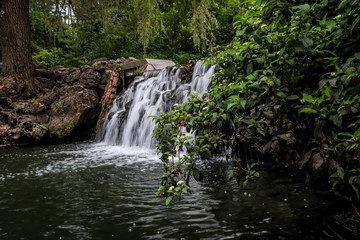 Naklejka na ściany i meble Beautiful waterfall in summer garden