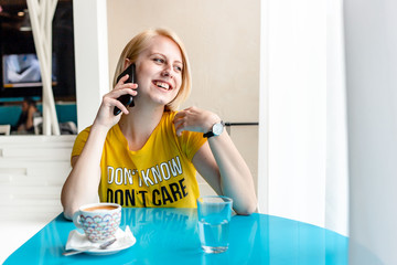 Girl in yellow t-shirt speaking on the phone with someone, laughing.