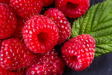 juicy fresh natural raspberries on a dark stone background