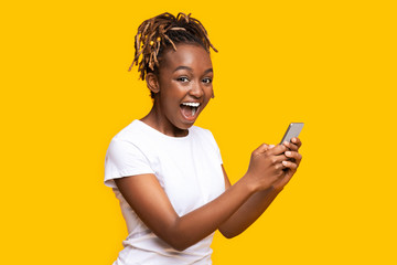 Excited black woman using mobile phone, got new nice app