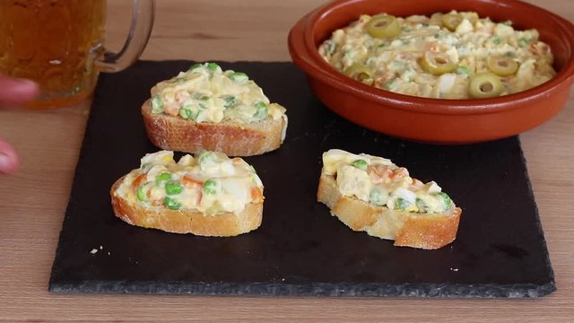 Plato de ensaladilla rusa con unos trozos de pan con ensaladilla rusa