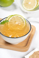 Taiwanese food - delicious cold drinking dessert Aiyu ice jelly in a white bowl and background with green lemon and mint topping, close up.