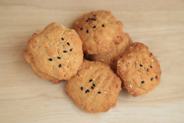 Tasty sesame cookies on wooden plate.