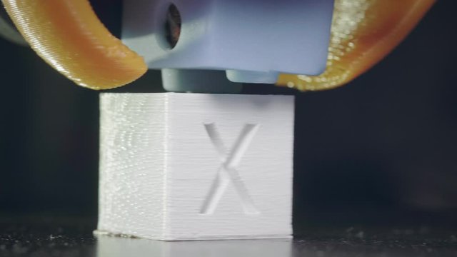 The 3D printer prints an abstract cube shape from white abs plastic. 3D printer head in action. An automatic three-dimensional 3d printer performs plastic. Macro