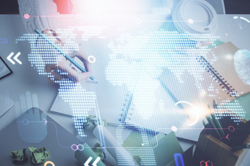 Double exposure of hands making notes with world map hologram and data theme icons. Concept of international network data.