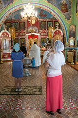 Godmother with kid wearing chrisom stand in the Orthodox church. Mother standing close to...