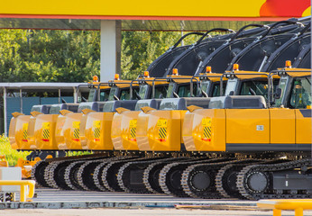 New Excavators are lined up in a parking lot.