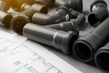 Plumbing pipes and project drawing on a concrete background.