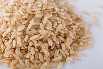 raw brown rice on white acrylic background