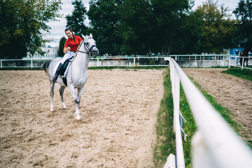 Female jockey riding horse on field