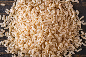 raw brown rice on dark rustic wooden background