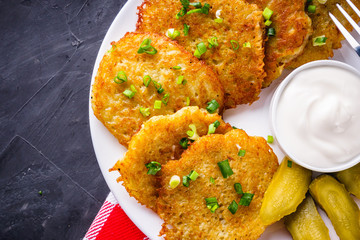 Delicious crispy potato pancakes on dark stone background