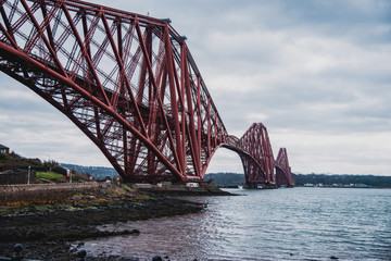Puente de Forth rojo de la ciudad de Edimburgo sobre el agua con rocas