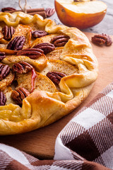 crispy apple galette with pecans on a rustic wooden background