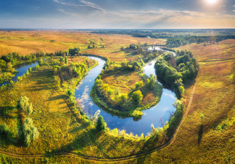 Aerial view of beautiful curving river at sunrise in summer. View from air. Turns of river, green...