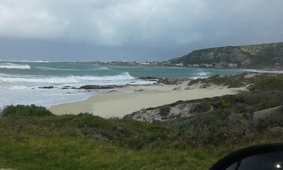 The waves hit the sandy beaches in the gloomy bays on the road to Cape Agulhas , South Africa