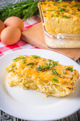 Delicious potato casserole with egg and cheese on a gray wooden background