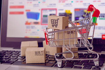 Shopping online. cardboard box with a shopping cart logo in a trolley on laptop keyboard. Shopping...