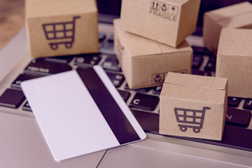  Shopping online. Credit card and cardboard box with a shopping cart logo on laptop keyboard. Shopping service on The online web. offers home delivery.