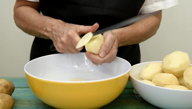 Las manos de una mujer cortan las patatas en rodajas
