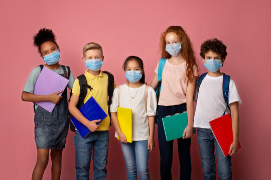 Health care and education. Portrait of schoolchildren wearing protective masks against pink background