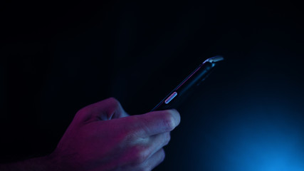 Hand using a smart phone in close up on a black background	
