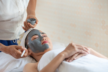 Beautiful Asian woman in mask on face in spa beauty salon, enjoying and relaxing time, skin care and healthcare concept