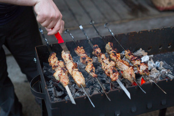 Man is frying meat pork on the grill. Shish kebab for summer party on a skewer.