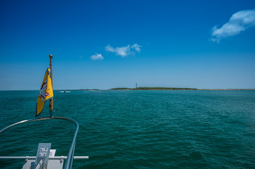 The bow of a Great Loop Cruiser yacht with the Cape Lookout Lighthouse in the distance. 