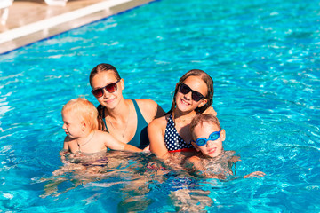 Happy children having fun at the pool during summer vacation.