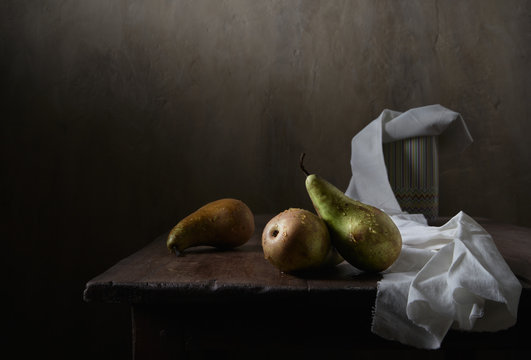 Green pears in drops of water. Still life in a low key