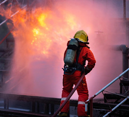 Firefighters using water fog spraying down fire from oil rig factory explosion