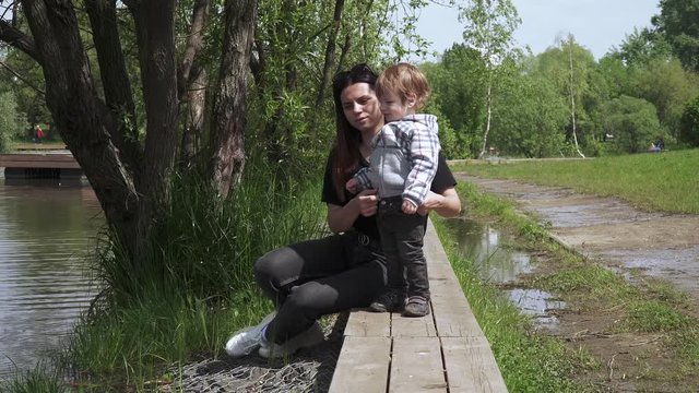Boy with mom sit on a wooden pier