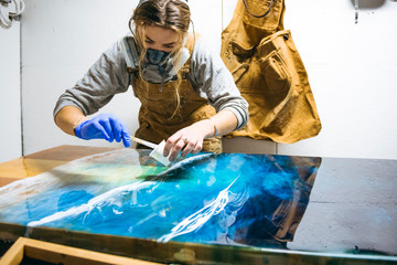 Female resin artist using simple materials to perfect artwork