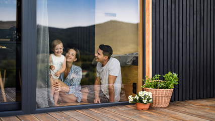 Young family with small daughter indoors, weekend away in container house in countryside. - obrazy, fototapety, plakaty